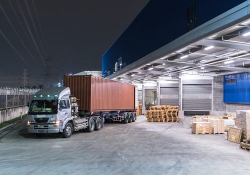 Truck is carrying container is parking in front warehouse at night time